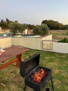 a grill in a yard with a picnic table at DAR AZAIEZ El Haouaria Villa 4 Chambres climatisé belle piscine in El Haouaria
