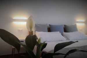 アルゲーロにあるcasa vacanze Gente di mareのベッドルーム1室(白い枕と植物付)