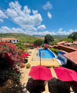 a swimming pool with red umbrellas and a resort at Hotel Hicasua y Centro de Convenciones in Barichara