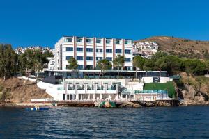 a large white building on a hill next to the water at Vira Otel Suites in Sinop