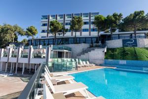 a swimming pool with lounge chairs in front of a building at Vira Otel Suites in Sinop