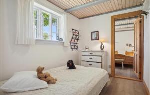 un osito de peluche sentado en una cama en un dormitorio en Mlletoften, en Thyholm