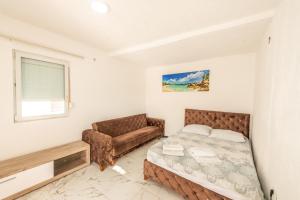 een slaapkamer met een bed en een bank bij Apartmani Medovic in Ulcinj