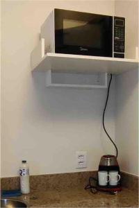 a microwave on a shelf above a kitchen counter at Flat em frente a praia Macaé in Macaé