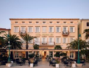 a large building with tables and chairs in front of it at Hotel Apoksiomen in Mali Lošinj