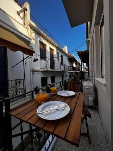a wooden table with plates and utensils on a balcony at Orfeas Luxury Rooms & Studio in Skopelos Town