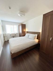 een slaapkamer met een groot bed, houten vloeren en een raam bij Quiet, Luxury Apt in Dublin. in Dublin