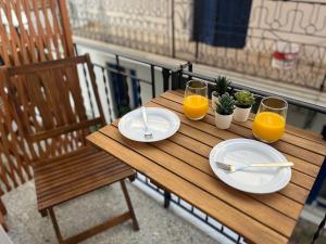 a wooden table with two plates and two glasses of orange juice at Orfeas Luxury Rooms & Studio in Skopelos Town