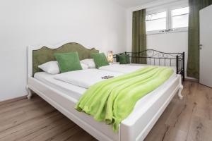 - un grand lit blanc avec une couverture verte dans l'établissement Dalila Appartements, à Sankt Michael im Lungau