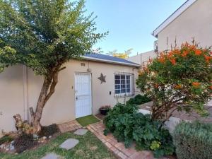 una piccola casa bianca con un albero in cortile di Cozy Garden Cottage! a Grahamstown