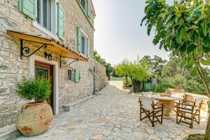a patio with a table and chairs and a building at Villa Aurora Paxos in Anemogiannátika