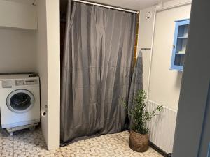 een wasmachine in een badkamer met een douchegordijn bij 120 kvm lejlighed med have i kælderniveau in Tølløse