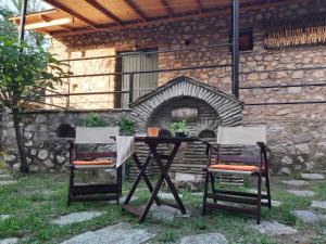 a table and two chairs in front of a fireplace at Potamolithos Suites 2 in Konitsa