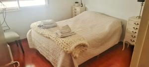 1 dormitorio pequeño con 1 cama blanca y 2 toallas en ROSARIO Oroño y Cordoba COCHERA en Rosario