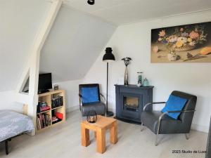 a living room with two chairs and a fireplace at De Til Heelsum in Heelsum