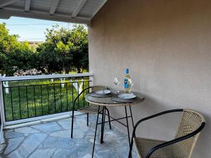 斯科派洛斯的住宿－Skapin house，阳台上配有一张桌子和两把椅子,并提供一瓶葡萄酒