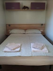 a bed with two towels sitting on top of it at Mobile Home Pinija in Jezera