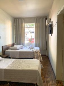 a hotel room with two beds and a window at Hotel Ideal in Chapecó