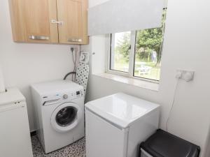 a small laundry room with a washing machine and a window at The Cottage in Talbenny