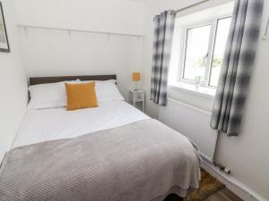 1 dormitorio con 1 cama blanca y ventana en The Cottage en Talbenny