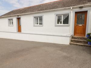 Casa blanca con puerta y ventanas marrones en The Cottage en Talbenny