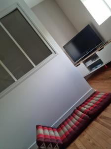 Chez Lofred 1 في Four: أريكة حمراء وبيضاء في غرفة بها تلفزيون