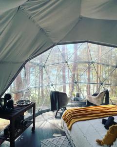 ein Schlafzimmer in einem Zelt mit einem Bett und einem Schreibtisch in der Unterkunft Skywoods.glamping in Molėtai