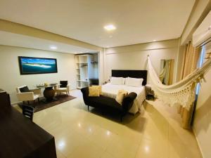a bedroom with a bed and a living room at Hotel Palace Santarém Brasil in Santarém