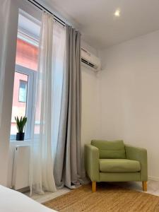 einem grünen Stuhl vor einem Fenster in der Unterkunft Apartament la casă în Centrul Orăștiei in Orăştie