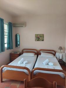 エディプソスにあるKoyias Villageのツインベッド2台(緑のカーテン付)が備わる客室です。