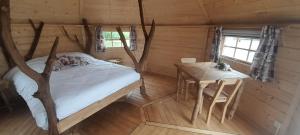 ein Schlafzimmer mit einem Bett und einem Tisch in einer Hütte in der Unterkunft Les Cabanes Flottantes in Givrauval