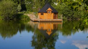 a small wooden house sitting on top of a lake at Les Cabanes Flottantes in Givrauval