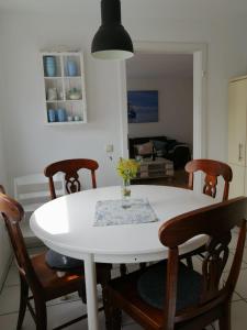 einen weißen Tisch mit Stühlen und eine Vase mit Blumen darauf in der Unterkunft Wellenbude in Otterndorf + 26 Fotos