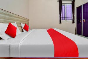 a bedroom with a white bed with red pillows at OYO Flagship Emerald Inn in Pīlamedu