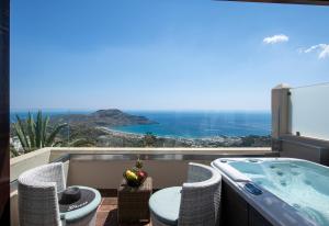 a balcony with a tub and chairs and a view at Stefanos Village Hotel in Plakias
