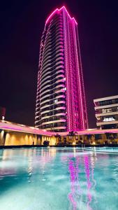 a large building with pink lights on it at night at LUX Deniz Manzaralı Tuzlu Havuz Su tadını çıkarın. in Konak