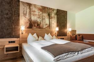a bedroom with a large bed with a painting on the wall at Landhaus Ifangl in Mayrhofen