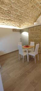 uma sala de jantar com uma mesa e cadeiras brancas em Le case di Roberto em Gioia del Colle