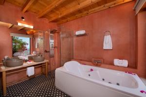 a bathroom with a large tub and two sinks at Stefanos Village Hotel in Plakias