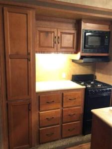 cocina con armarios de madera, fogones y microondas en Bass Capital Rentals LLC, en Quitman