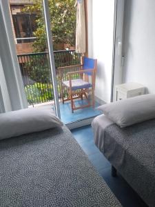 um quarto com 2 camas e uma varanda com uma cadeira em APARTAMENTO con TERRAZA VISTAS AL MAR em Lloret de Mar