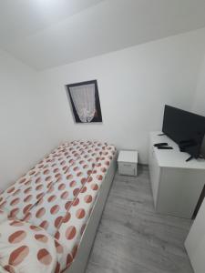 a white bedroom with a bed and a desk at Cabana Miraj in Groşii Ţibleşului