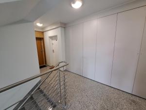un escalier dans une pièce avec des armoires blanches dans l'établissement Bursztynowy dom Międzywodzie Apartament z 1 sypialnią, à Międzywodzie