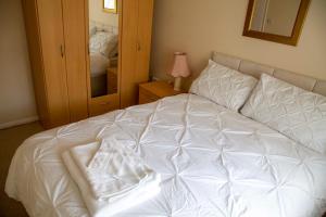 a white bed in a bedroom with a mirror at St Margaret's Bay Holiday Let in St Margarets at Cliff