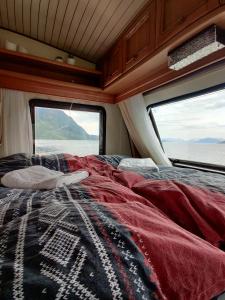 Una cama en la parte trasera de una furgoneta con dos ventanas en Captain's Hideout, 