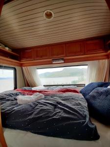 una cama en la parte trasera de una caravana con una ventana en Captain's Hideout, 
