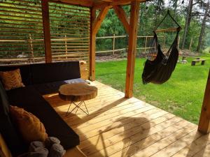 eine abgeschirmte Veranda mit einem Sofa und einer Hängematte in der Unterkunft Sosnowy Plan in Józefów