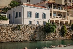 a white building on a stone wall next to a river at Palazzo di Sitia Luxury Suites in Sitia
