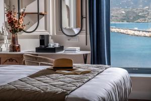 1 dormitorio con 1 cama con sombrero y ventana en Palazzo di Sitia Luxury Suites en Sitia