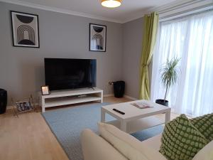 a living room with a couch and a tv at Green Door-The Malting- Specious 1st Floor-One Bedroom Apartment -Fully Furnished-Quiet- Free Parking -Dunstable in Dunstable
